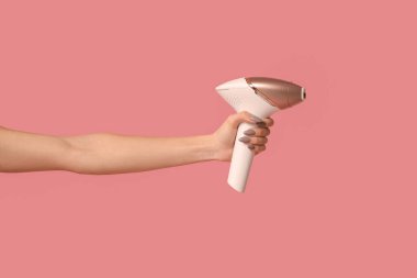 Pembe arka planda modern stil fotoğraf makinesi olan kadın eli.