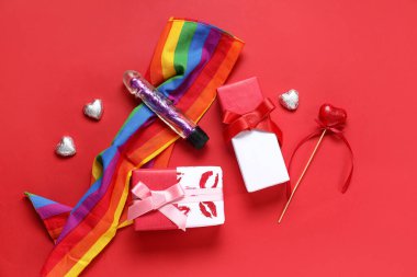Vibratörlü gökkuşağı LGBT bayrağı ve kırmızı arka planda hediyeler. Sevgililer Günü kutlaması