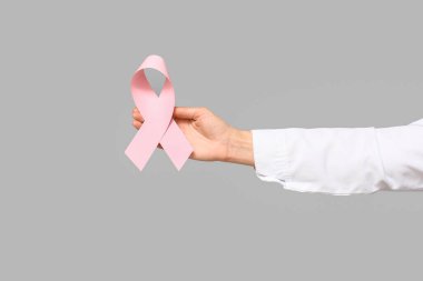 Gri arka planda pembe kurdeleli bir kadın doktor. Göğüs kanseri farkındalığı konsepti