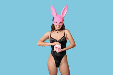 Tavşan maskeli güzel bir Asyalı kadın ve mavi arka planda hediye kutusu olan seksi bir iç çamaşırı.