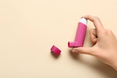 Bej arka planda astım spreyi olan bir çocuk eli.