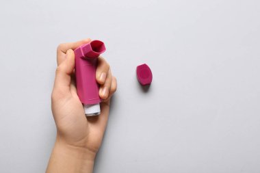 Beyaz arka planda astım spreyi olan bir çocuk eli.