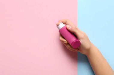 Renk arkaplanında astım spreyi olan bir çocuk eli