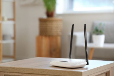 Modern Wi-Fi yönlendirici, oturma odasındaki ahşap masada, yakın plan.