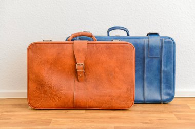 Mavi ve kahverengi eski deri bavullar odada yerde.