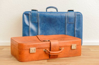 Mavi ve kahverengi eski deri bavullar odada yerde.