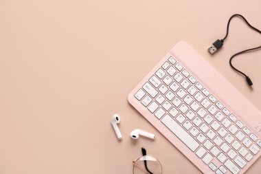 Gözlük, kulaklık, kablo ve bilgisayar klavyesi pembe arka planda. Üst görünüm
