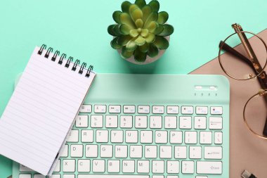 Lezzetli bilgisayar klavyesi, gözlük ve renkli arkaplan üzerine not defteri. Üst görünüm