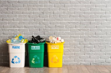 Gri tuğla duvarın yanında farklı çöp kutularıyla dolu. Geri dönüşüm kavramı