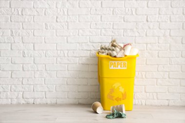 Beyaz tuğla duvarın yanında kağıt levhası olan bir çöp kutusu. Geri dönüşüm kavramı