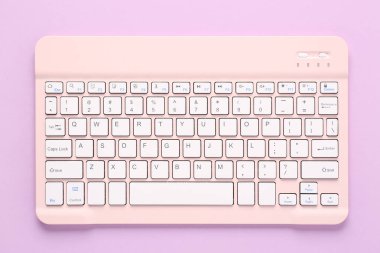 Leylak arka planında pembe bilgisayar klavyesi. Üst görünüm