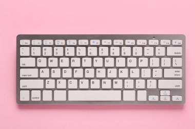 Pembe arka planda gri bilgisayar klavyesi. Üst görünüm