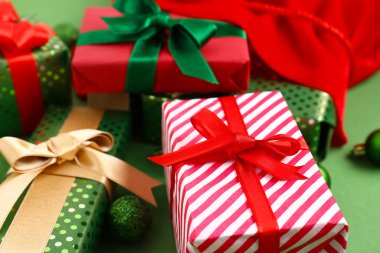 Yeşil arka planda Noel hediyeleri ve topları olan güzel kompozisyon, yakın plan.