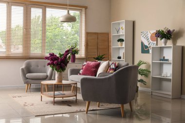 İçinde vazoda leylak çiçekleri olan modern oturma odası.