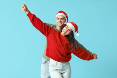 Mavi arka planda Noel süveteri giyen mutlu genç çift