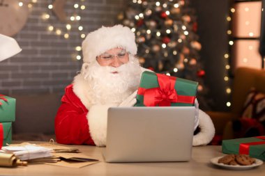 Hediye kutusu olan Noel Baba akşam evde video sohbeti yapıyor.