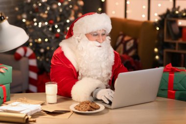 Akşam evde dizüstü bilgisayar kullanan Noel Baba.