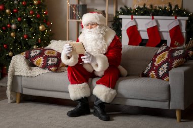 Evdeki kanepede oturan mektuplarla Noel Baba.