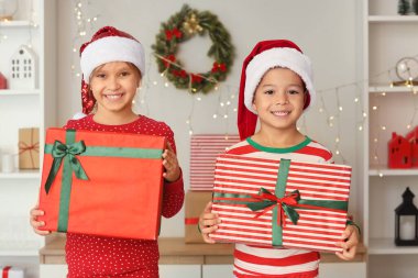 Evde Noel 'de hediye kutularıyla elf gibi giyinmiş şirin mutlu çocuklar.