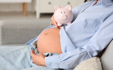 Evdeki kanepede kumbaralı hamile bir kadın oturuyor, yakın plan. Annelik Faydası konsepti