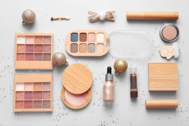 Dekoratif kozmetik ürünleri ve ışık arka planında Noel süslemeleri içeren kompozisyon