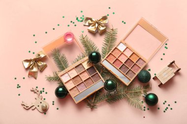 Dekoratif kozmetik ürünleri, köknar dalları ve renk arkaplanı üzerine Noel süslemeleri içeren kompozisyon