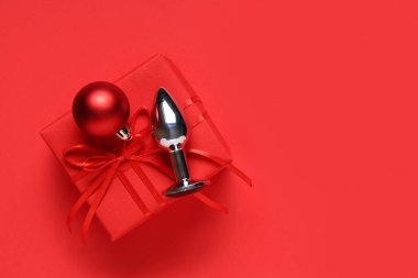 Anal tıkaç, Noel topu ve kırmızı arka planda hediye kutusu.