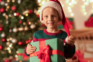 Noel Baba şapkalı şirin küçük çocuk evde Noel hediyesiyle