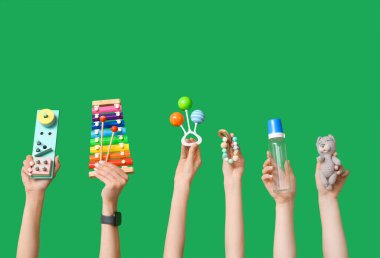 Yeşil arka planda farklı bebek aksesuarları olan kadın elleri.