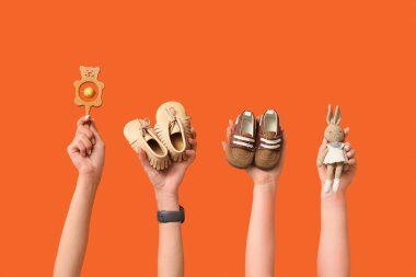 Bebek poposu ve turuncu arka planda oyuncakları olan kadın elleri.