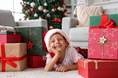 Noel Baba şapkalı şirin çocuk evde yerde yatıyor.
