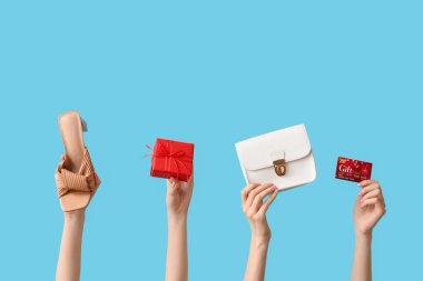 Şık aksesuarları olan kadın eller, renkli arka planda Noel hediyesi ve kart.