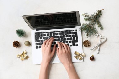 Modern dizüstü bilgisayarı olan kadın eller ve arka planda Noel süslemeleri
