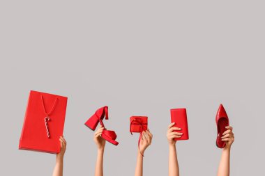 Aksesuarlı birçok kadın eli, Noel hediyesi kutusu ve gri arka planda alışveriş çantası.