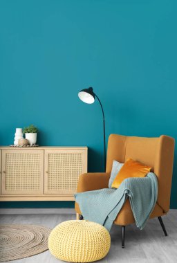 Mavi duvarın yanında rahat koltuk ve tuvaleti olan modern bir oda.