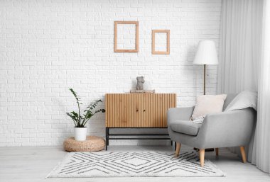 Rahat koltuğu ve beyaz tuğla duvarın yanında klozeti olan modern bir oda.