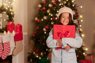 Noel Baba şapkalı küçük kız evde Noel hediyesiyle