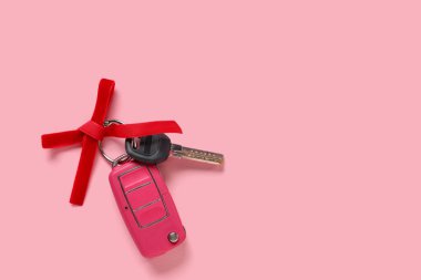 Pembe arka planda kırmızı fiyonklu yeni arabanın hediye anahtarları.
