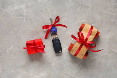 Yeni araba anahtarlarıyla hediye kutusu ve grunge gri arka planda tahta oyuncak.