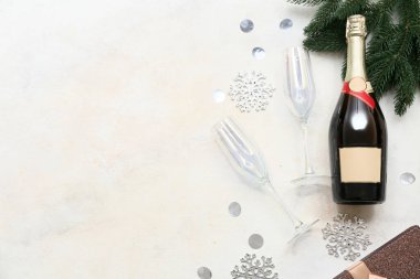 Noel süslemeleri, bardaklar ve köknar dalı olan bir şişe şampanya.