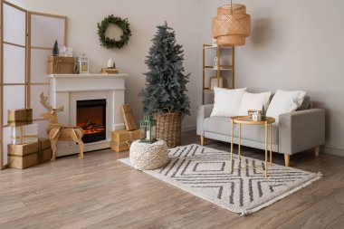 Oturma odasının içinde şömine, kanepe ve Noel ağacı var.