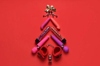 Kırmızı arka planda farklı seks oyuncaklarından yapılmış Noel ağacı