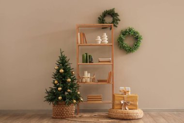 Oturma odasının içinde raf ünitesi, Noel ağacı ve çelenk var.