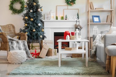 Oturma odasının içinde Noel ağacı, şömine ve koltuk var.
