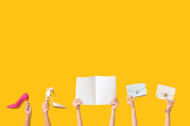 Boş şarjörlü kadın elleri, şık çantalar ve sarı arka planda topuklu ayakkabılar.