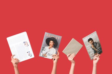 Farklı dergilere, gazetelere ve kırmızı arka plana sahip kadın elleri