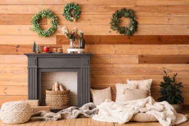 İçinde Noel çelenkleri, şömine rafı ve yastıklar olan oturma odası.