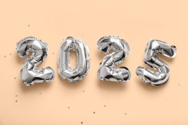 Sarı arka planda folyodan yapılmış 2025 model balon. Noel kutlaması