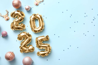 Mavi arka planda noel topları olan folyodan yapılmış 2025 numaralı figür