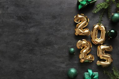 Noel topları, hediye kutuları ve siyah arka planda köknar dalları olan folyodan yapılmış 2025 model.